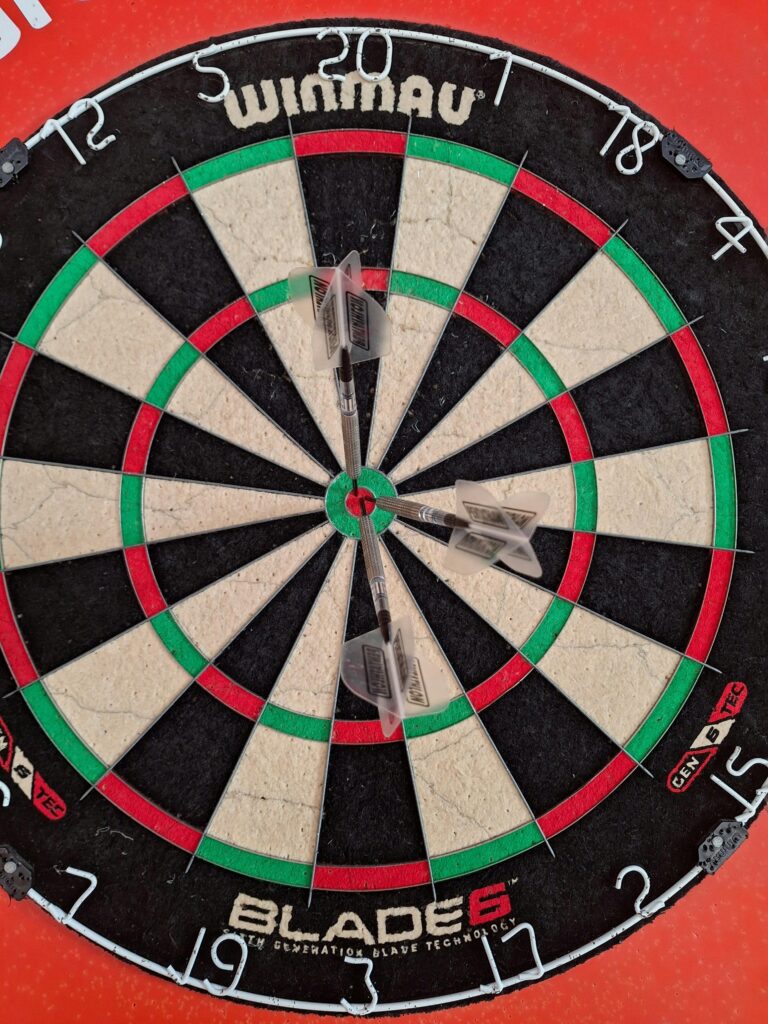 Detailed close-up of a dartboard with darts scoring close to bullseye.