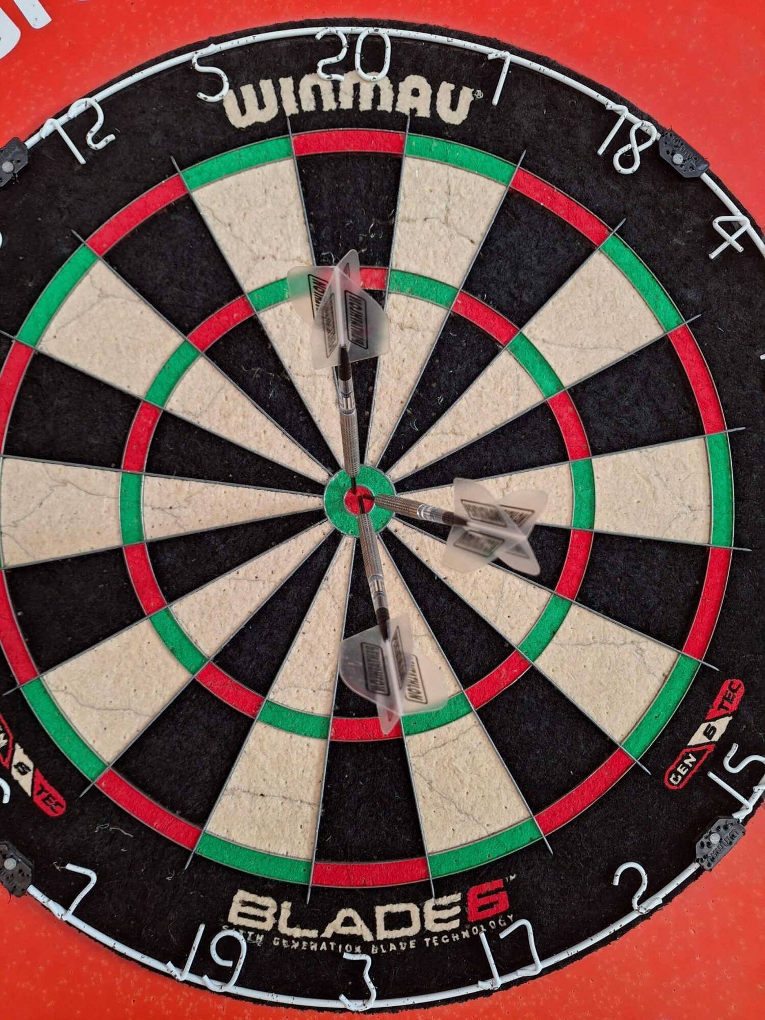 Detailed close-up of a dartboard with darts scoring close to bullseye.